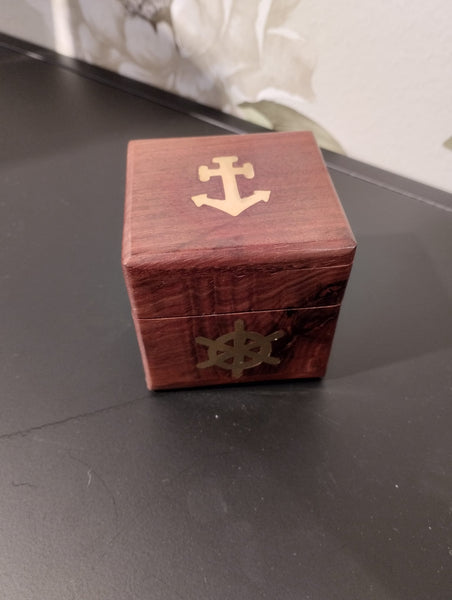 Fin, dekoartivt träask med nautisk motiv som innehåller 6 mindre tärningar för att spela t.ex. maxi yatzee.  Material: trä, mässing  Mått Träask: 7x7x7 cm  Mått Tärningar: 2x2x2 cm